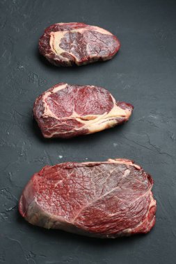 Koyu gri desenli masada çiğ et parçaları, düz yatıyordu.