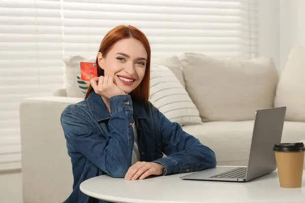 Happy woman with credit card near laptop at home. Online shopping