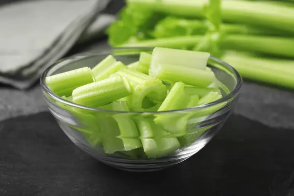 Bowl with fresh green cut celery on grey table, closeup