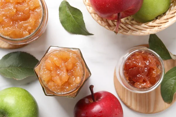 Delicious apple jam and fresh fruits on white table, flat lay
