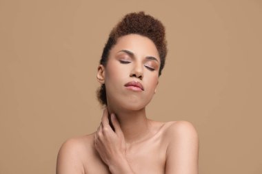 Portrait of beautiful young woman with glamorous makeup on light brown background