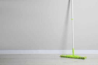 Kapalı alandaki duvarın yanında plastik saplı paspas. Metin için boşluk