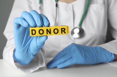 Doktor, beyaz masada küplerden yapılmış bir donör tutuyor, yakın plan.