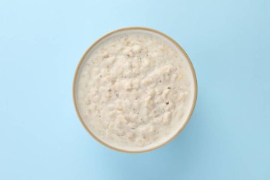 Açık mavi masada, tabakta kaynamış yulaf ezmesi.