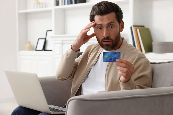 Zaszokowany Człowiek Laptopem Kartą Kredytową Fotelu Domu Uważaj Oszustwo — Zdjęcie stockowe