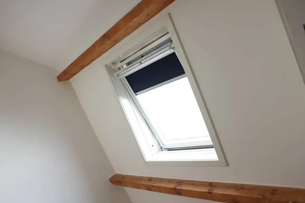 Roof window on slanted ceiling indoors, low angle view