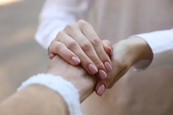Trust and support. Women joining hands on blurred background, closeup