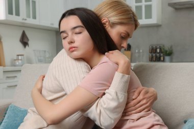 Anne, üzgün kızını evde teselli ediyor. Gençlik sorunları