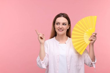 Sarı elli mutlu kadın pembe arka planı işaret ediyor, mesaj için yer var.