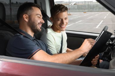 Ehliyet kursu. Otoparkta sınavı geçen mutlu öğrenci.