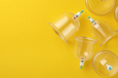 Sarı arka planda plastik bardaklar, metin için yeri olan düz yataklar. Fincan terapisi.