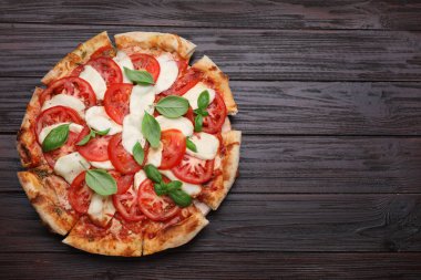 Domatesli lezzetli Caprese pizzası, mozzarella ve fesleğen, koyu ahşap masa, üst manzara. Metin için boşluk