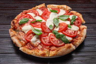 Domatesli lezzetli Caprese pizzası, siyah ahşap masada mozzarella ve fesleğen, yakın plan.