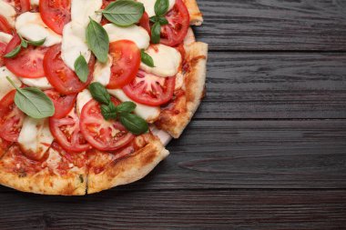 Domatesli lezzetli Caprese pizzası, mozzarella ve fesleğen, koyu ahşap masa, üst manzara. Metin için boşluk
