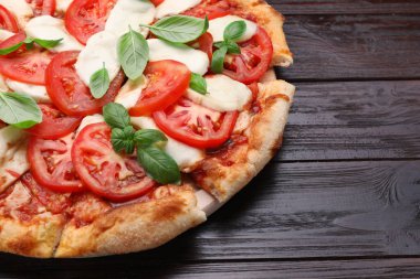 Domatesli lezzetli Caprese pizzası, siyah ahşap masada mozzarella ve fesleğen, yakın plan. Metin için boşluk