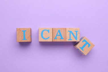 Motivasyon konsepti. Kelimeyi I Can 'dan I Can' a çevirerek mor arkaplandaki T harfi ile tahta küpü kaldırıyorum.