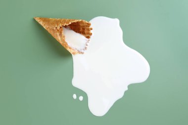 Yeşil arka planda erimiş dondurma ve gofret külahı.