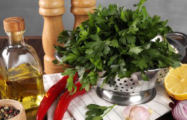 Taze maydanozlu Colander, baharatlar ve diğer ürünler ahşap masada.