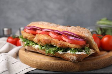 Gri ahşap masada şnitzel ile nefis bir sandviç.
