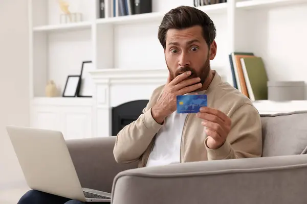 Zaszokowany Człowiek Laptopem Kartą Kredytową Fotelu Domu Uważaj Oszustwo — Zdjęcie stockowe