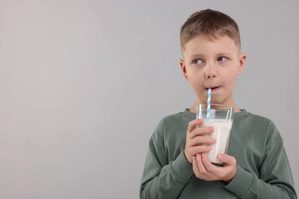軽い灰色の背景にガラスから新鮮なミルクを飲むかわいい少年 テキストのためのスペース — ストック写真