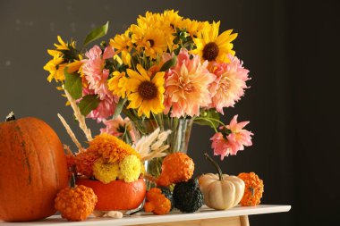 Güz kompozisyonu güzel çiçekler ve balkabakları beyaz masada koyu gri arka planda