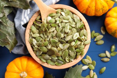 Çekirdekli kase, taze kabaklar ve mavi ahşap masa üzerinde kuru yapraklar, düz uzanmış