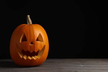 Ahşap masa üzerinde balkabağından yapılmış korkunç Jack O 'Lantern siyah arka planda, mesaj için yer var. Geleneksel Cadılar Bayramı dekorasyonu