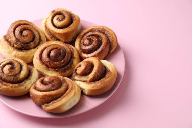 Pembe arka planda pek çok lezzetli tarçınlı rulo, yakın plan. Metin için boşluk