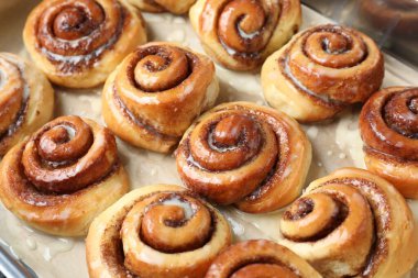 Tasty cinnamon rolls with cream on parchment paper, closeup clipart