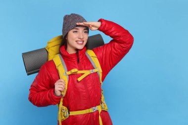 Sırt çantalı gülümseyen genç bir kadın açık mavi arka planda, mesaj için yer var. Etkin turizm