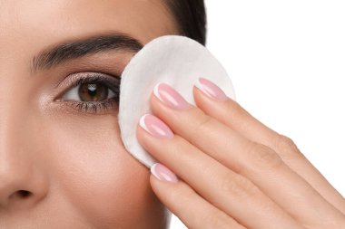 Beyaz arka planda pamuklu ped ile makyajı kaldıran güzel bir kadın.