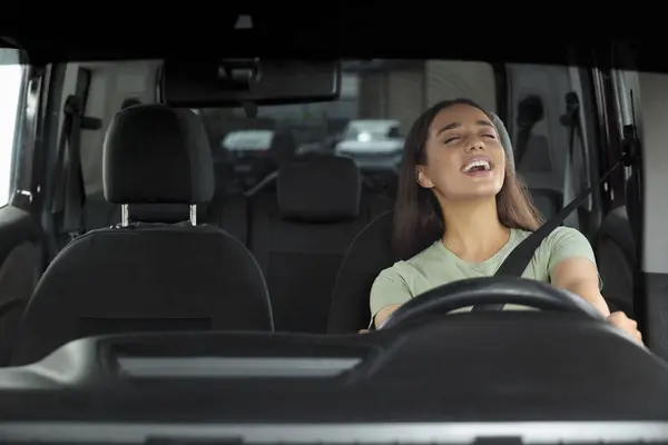 Listening to radio. Beautiful woman enjoying music in car, view through windshield