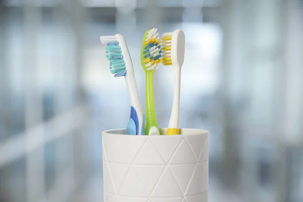 Plastic toothbrushes in holder against blurred background, closeup