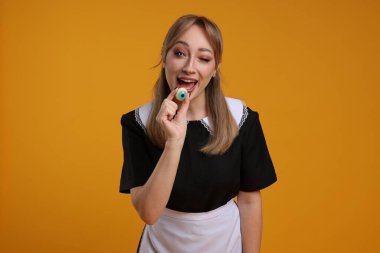 Turuncu arka planda dekoratif gözü olan korkunç hizmetçi kostümlü mutlu kadın. Cadılar Bayramı