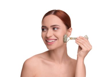 Young woman massaging her face with jade roller on white background