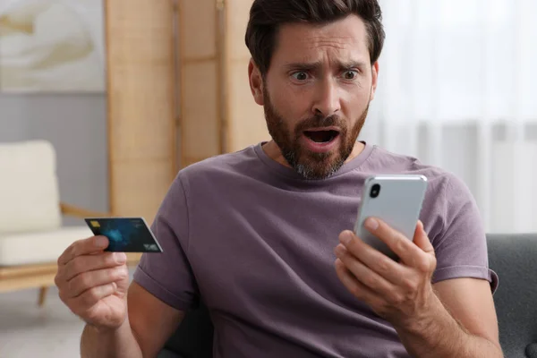 Zaszokowany Człowiek Kartą Kredytową Korzystający Smartfona Domu Uważaj Oszustwo — Zdjęcie stockowe