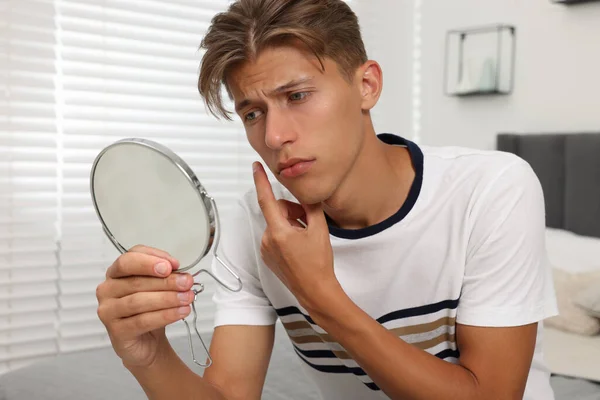 鏡を見つめている若い男は 屋内で顔にピンプルに触れました アクネ問題 — ストック写真