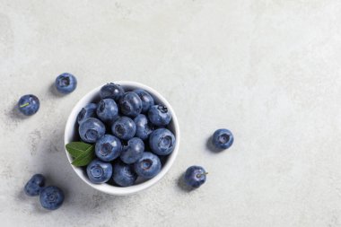 Açık gri masada bir kase taze yaban mersini. Metin için boşluk