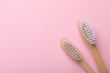 Pembe arka planda bambu diş fırçaları, düz yatış. Metin için boşluk