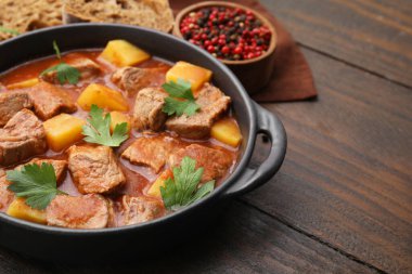 Tahta masadaki tencerede leziz gulaş, yakın plan. Metin için boşluk