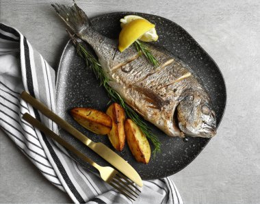 Gri masada servis edilen nefis pişmiş balık, üst manzara. Deniz ürünleri.