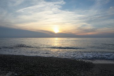 Gün batımında deniz ve tropik plaj manzarası.