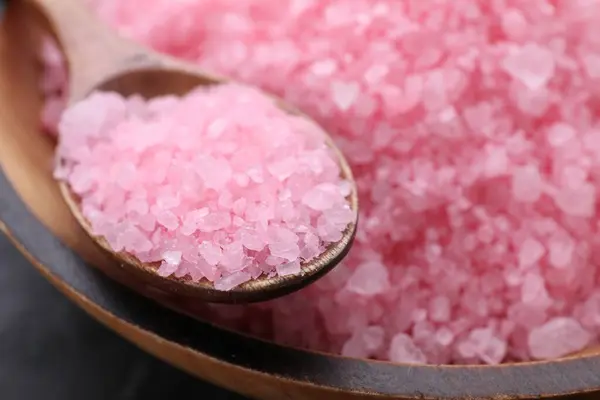 Spoon and pink sea salt in wooden bowl, closeup