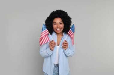 4 Temmuz - ABD 'nin Bağımsızlık Günü. Açık gri arka planda Amerikan bayrakları olan mutlu kadın.