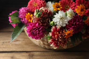 Güzel yabani çiçekler ve yapraklar hasır sepetin içinde ahşap masanın üzerinde, yakın plan