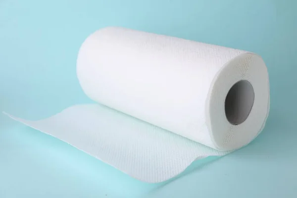 One roll of paper towels on light blue background, closeup