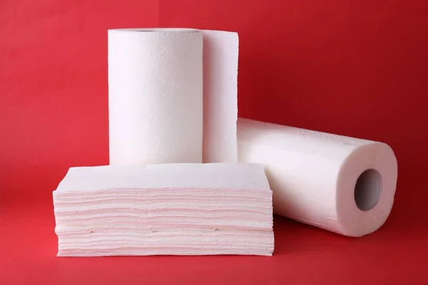 Rolls and stack of paper towels on red background