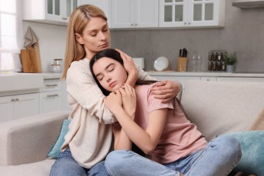 Anne, üzgün kızını evde teselli ediyor. Gençlik sorunları