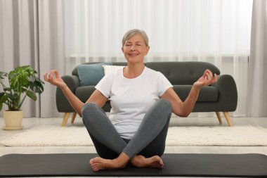 Mutlu son sınıf öğrencisi kadın evde yoga yapıyor.